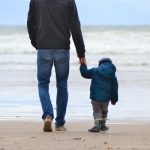 un homme marche sur la plage avec son enfant après une analyse génétique de paternité