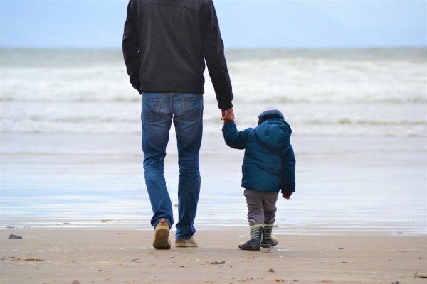 un homme marche sur la plage avec son enfant après une analyse génétique de paternité