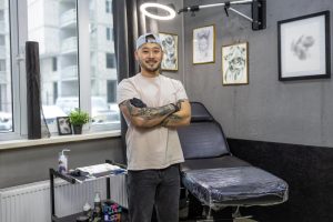 Portrait d'un bon tatoueur souriant dans son studio moderne avec son équipement professionnel