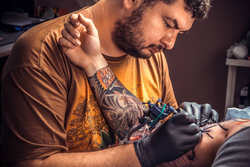 Gros plan d'un bon tatoueur en train de réaliser une pièce complexe sur le bras d'un client.