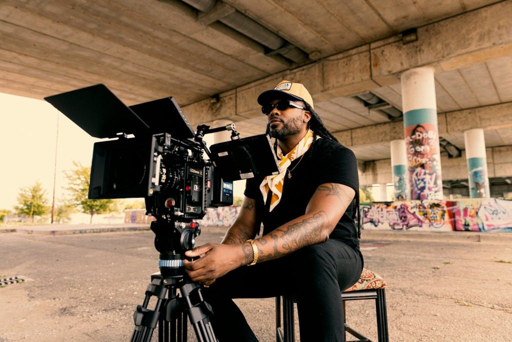 Man with camera under a bridge with graffiti