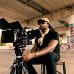 Man with camera under a bridge with graffiti
