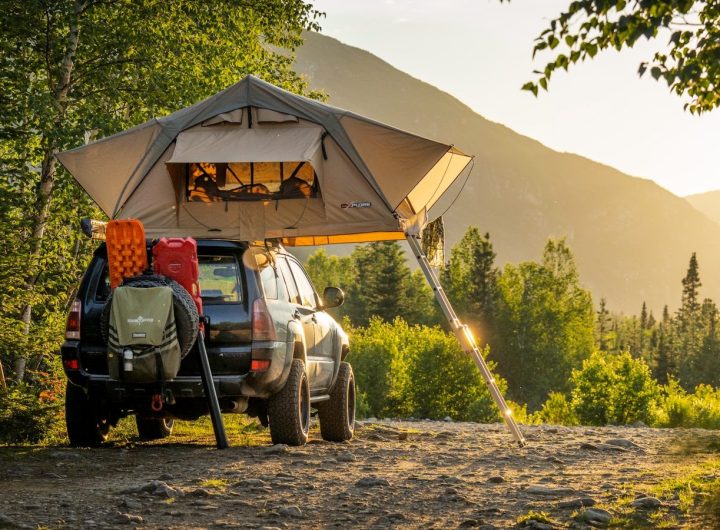 man in green jacket sitting on black and yellow camping chair near tent during daytime