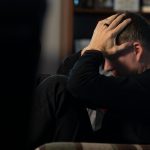 a man sitting on a couch holding his head in his hands