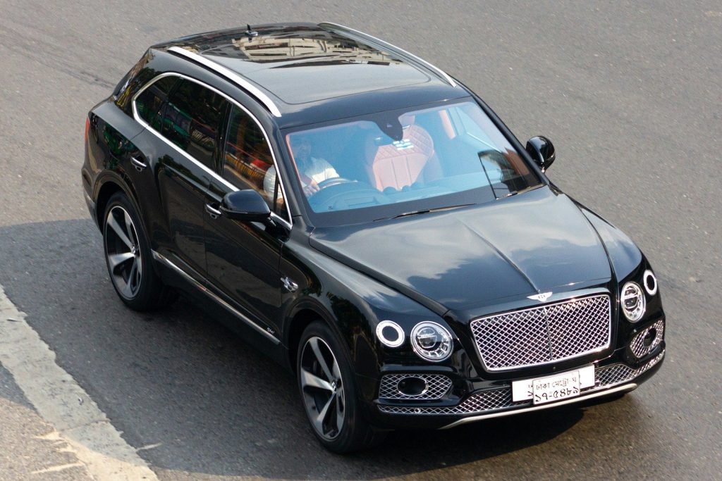 A black bentley suv drives on a road.